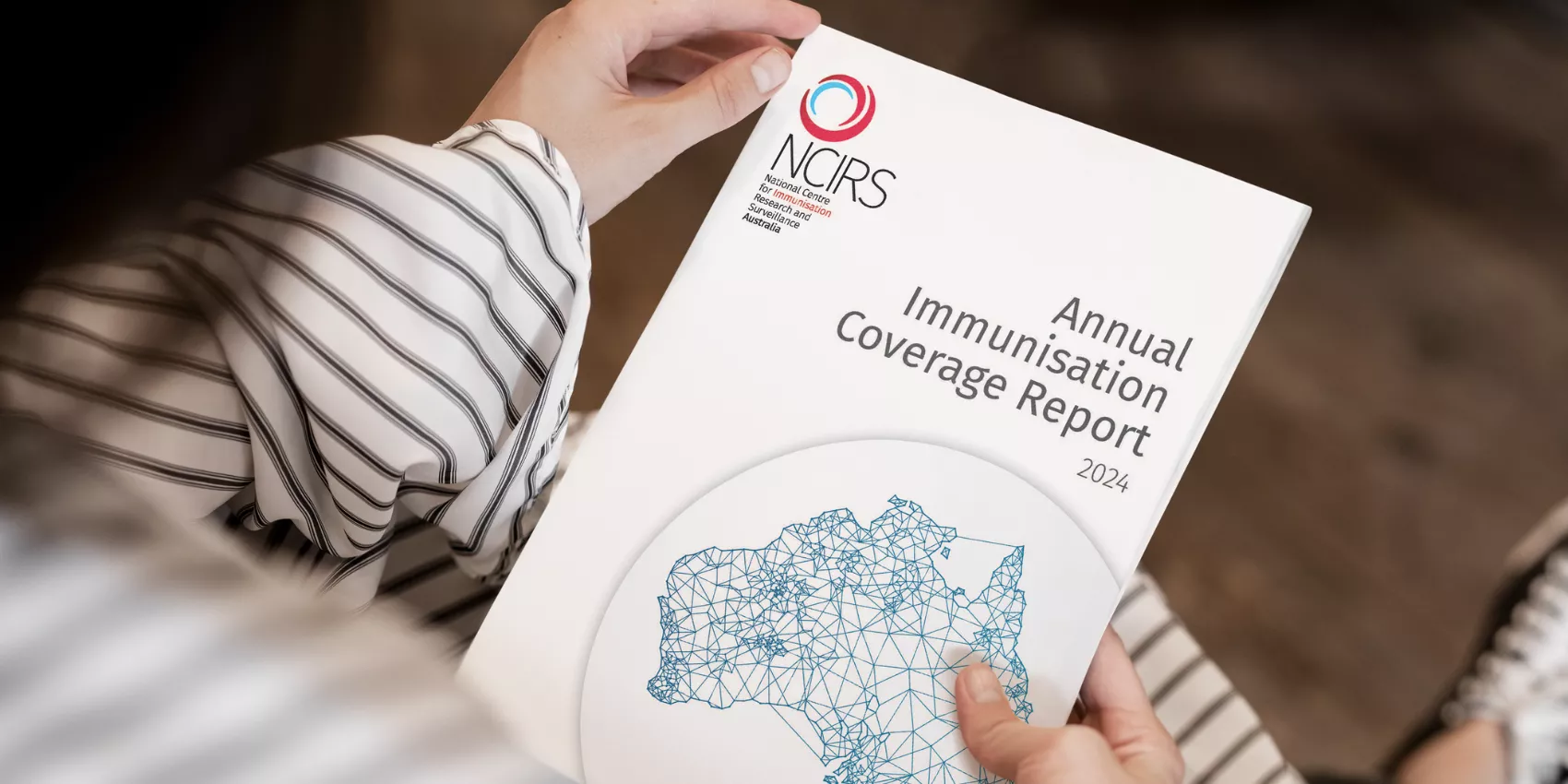 A person sitting holding the Annual Immunisation Coverage Report 2024