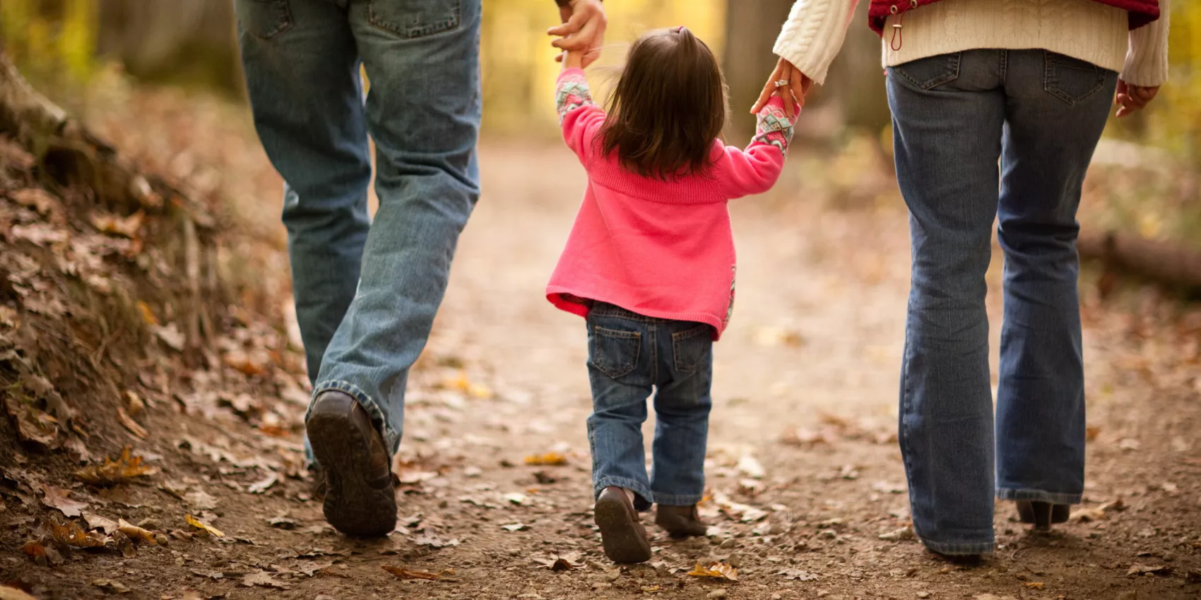 Parents walking their toddler down a dirt path