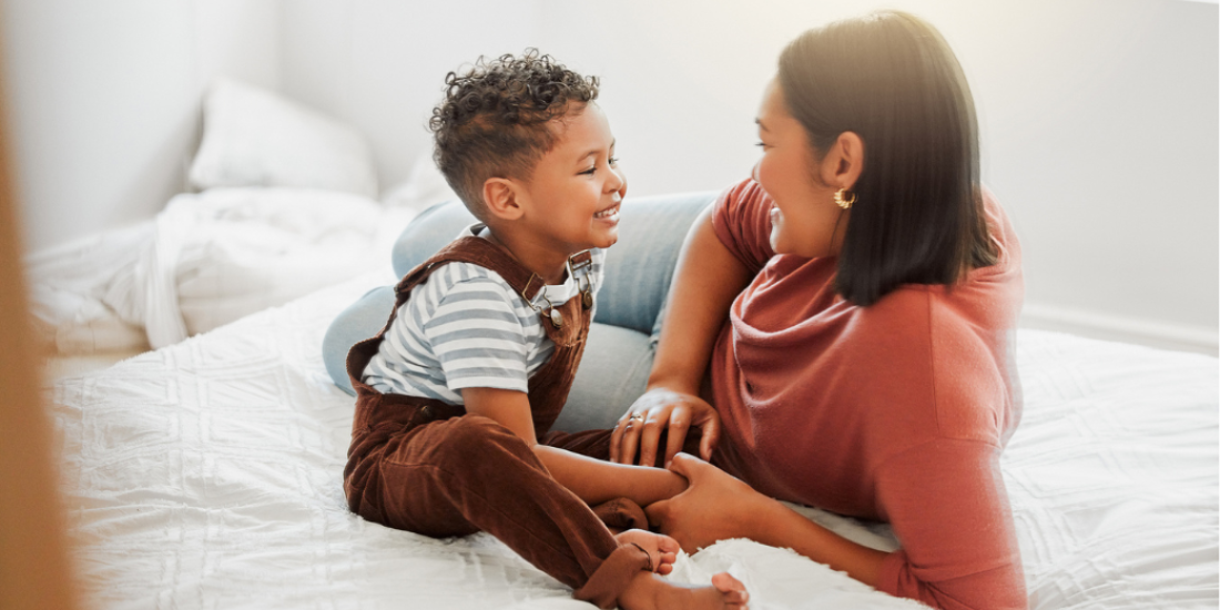 Image of mother and young son chatting on a bed