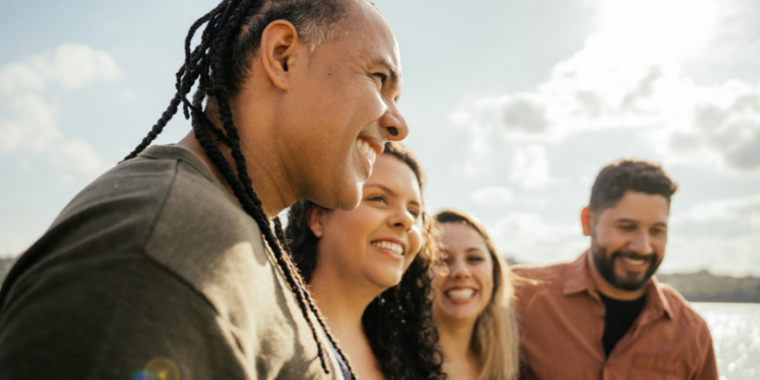 Four friends with arms around each other smiling