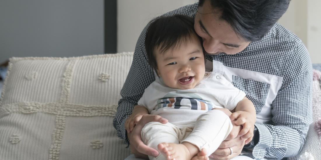 A father holding his toddler son sitting on a couch