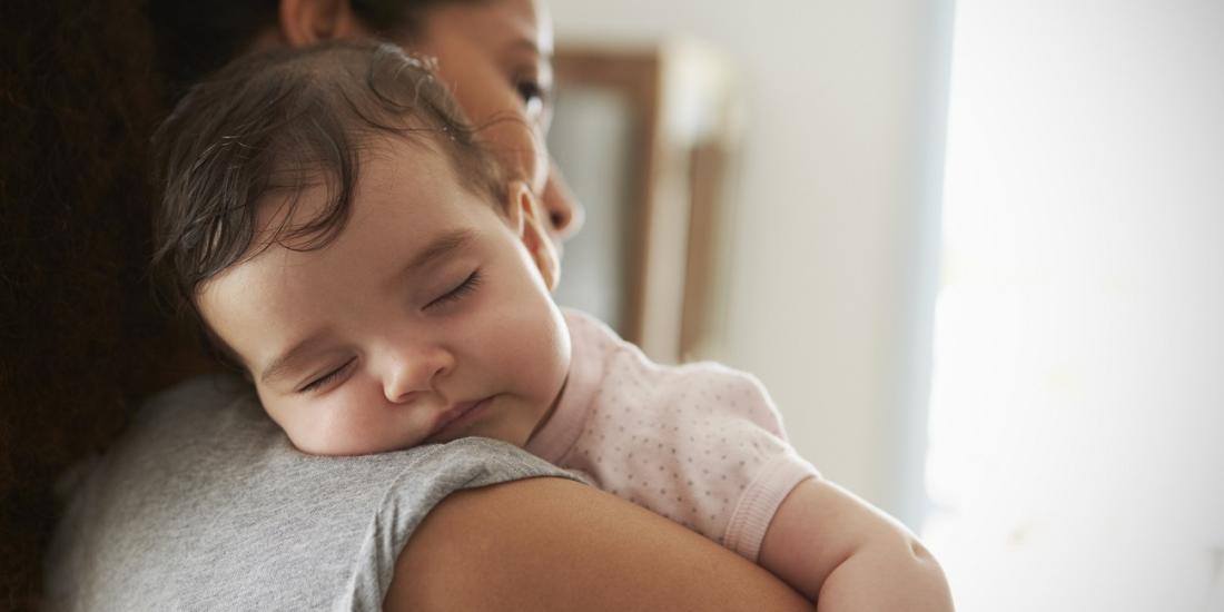 A toddler resting their head on the mother's shoulder