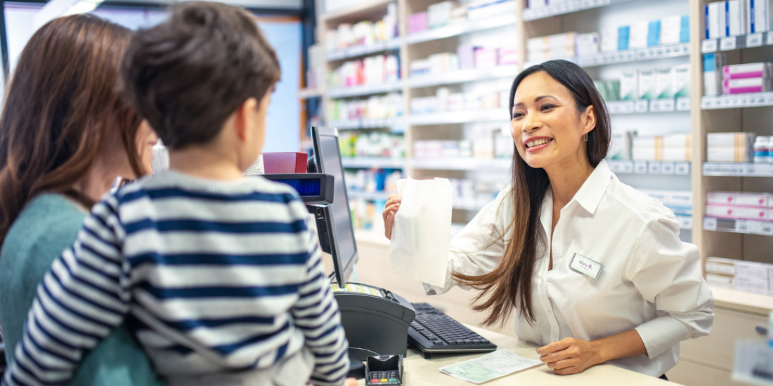 Image of mother holding her son talking to a pharmacist