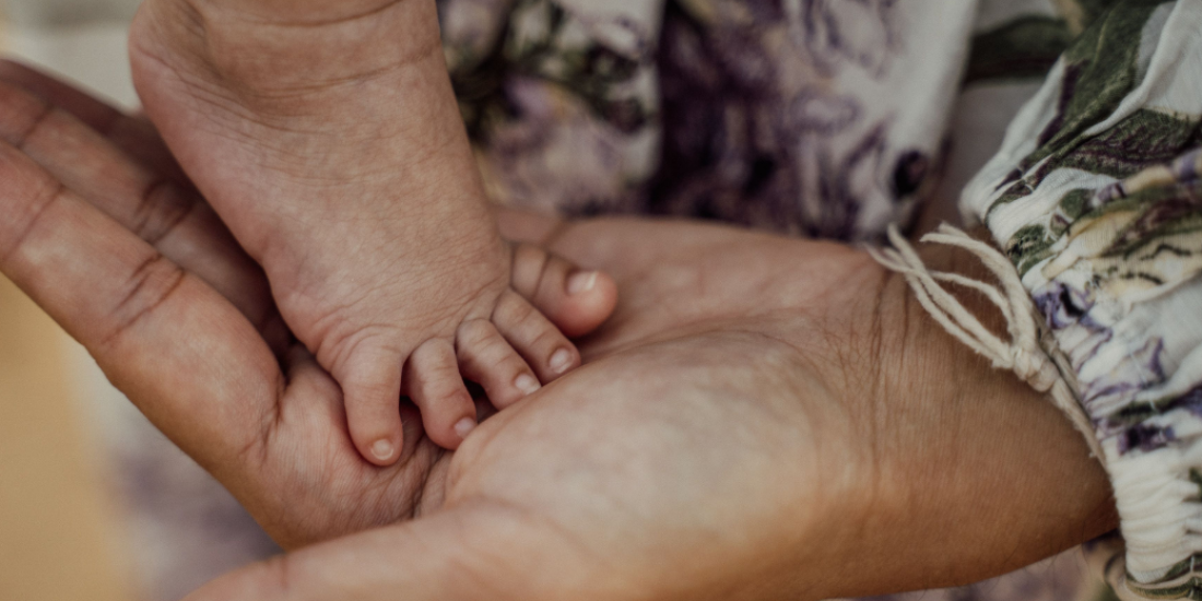Image of a baby's foot resting on mother's hand